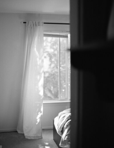 soft black and white film photo of bedroom, morning light through sheer curtains, film home lifestyle photographer