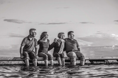 family of 4 embracing on dock in  a lake