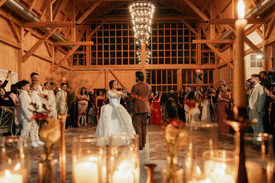 A bride and groom share their first dance in a rustic candle lit reception modern barn in Hampton New Jersey