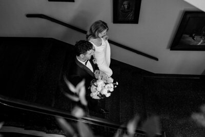 Bride and groom walking down the historic staircase at Rainier Club