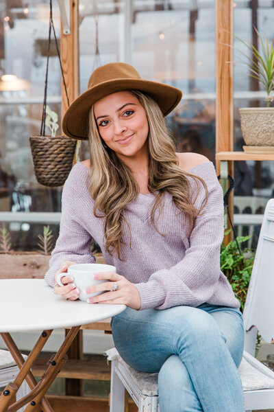 high school senior holding a cup of coffee sitting at a white table