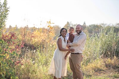 Family standing next to tall grass at the Gabriel Dumont Park in Saskatoon. Captured by Amanda Jordan Photography.
