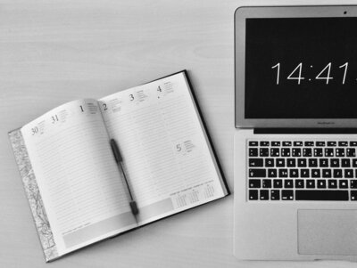A weekly planner next to a laptop, representing the timeline of designing a website in one week