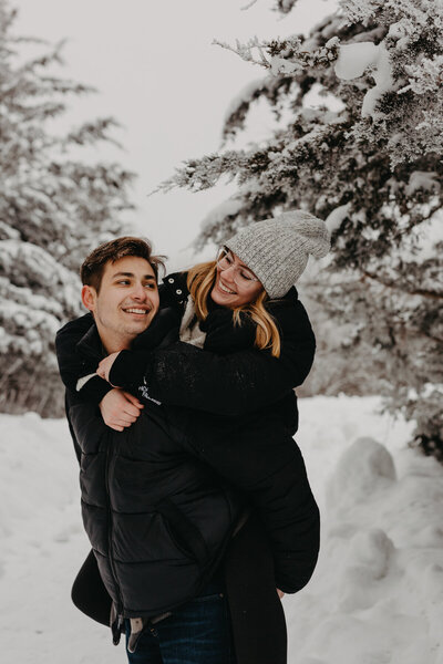 couple's snowy piggyback ride smiling picture