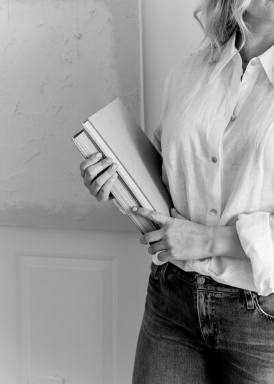Black and white image of woman holding a stack of books