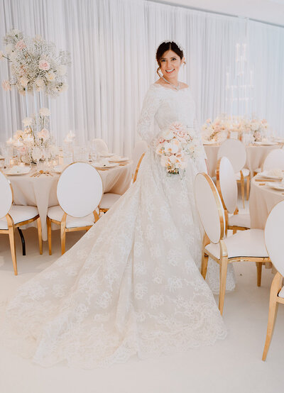 A bride and a groom's  luxury lakeside wedding ceremony in Munich with a floating floral backdrop by the lake. The bride wears an Elie Saab bridal dress, holding a bouquet.