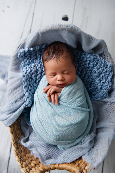 BABY IN BLUE FABRIC IN BASKET