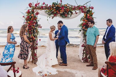 Bride and groom under arch at beach wedding in R
