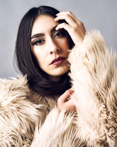 Woman in magazine-styled portrait with a fur jacket, dark hair and red lips
