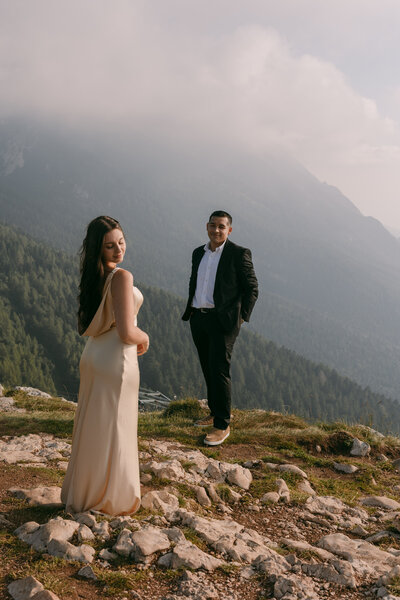 bride and groom standing on mountain side with mountains in the background
