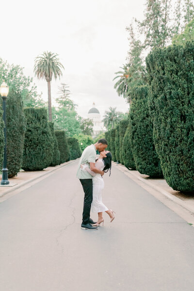 couple kissing in front of California State Capital Building during their engagement session in Sacramento