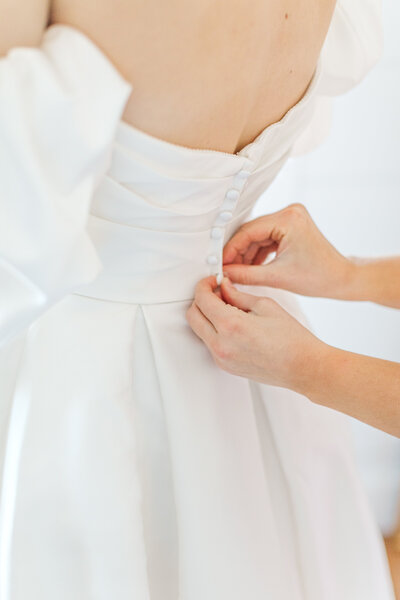 bride having her dress buttoned st. louis mo wedding photographer