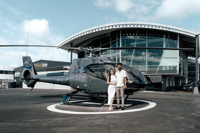 Helicopter parked with Nikhil and Pranali posing during engagement photoshoot in Auckland, captured by Zanthe Vorsatz.