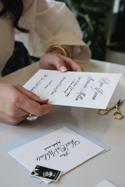 Hands holding a calligraphy wedding invitation
