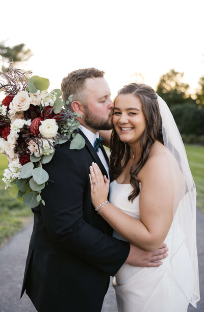 Virginia wedding photographer captures bride and groom holdin ghands and looking off to the side away from each other in a field with a hills behind them for a fall wedding