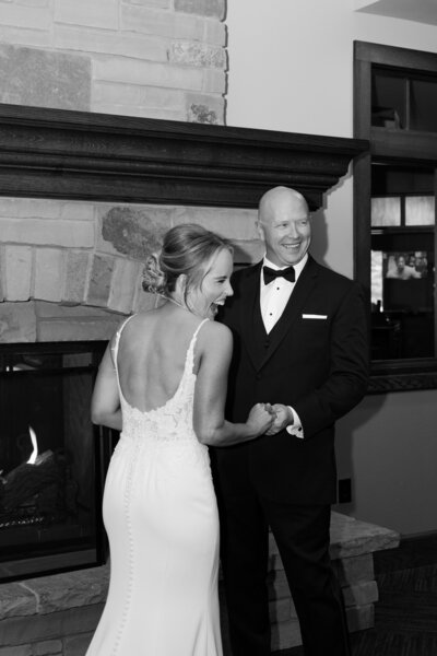 Black and white photo of bride and groom getting warm by the fireplace at the highlands golf club in billings, mt