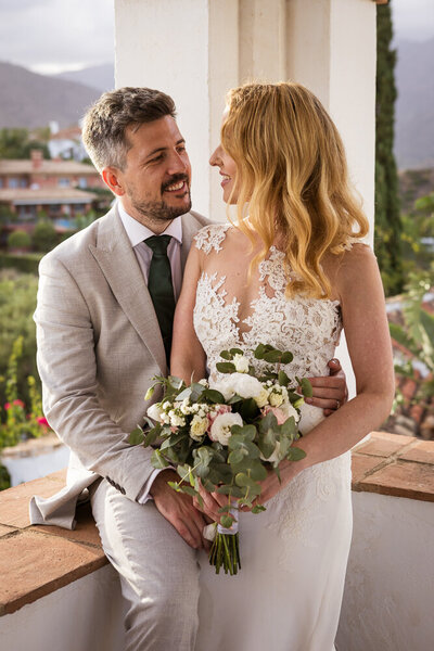 bride and groom embracing on the edge of the tower at their wedding venue