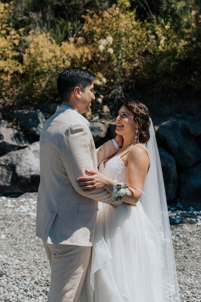 A candid and intimate moment shared between a bride and groom on the beach at Kitsap Memorial Park in Kitsap, WA