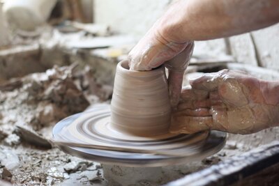 A studio close-up of a ceramicist throwing clay on a wheel in his studio, an example of Courtney's branding and artist spotlight photography