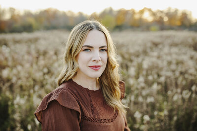 Headshot of London, ON premiere wedding photographer in brown dress looking at camera at golden hour.