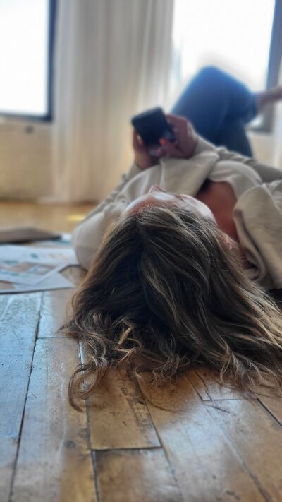 Julie laying on ground looking at Pinterest on her phone 