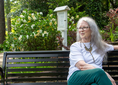 Female memoirs mentor sitting on park bench with white shirt