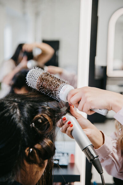 Stylist at Salon Beau carefully styling a client’s hair for a low-maintenance, natural finish.