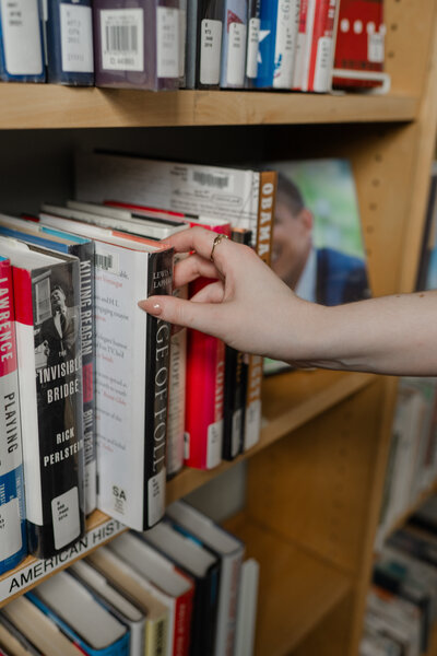 A hand reaching for a book on a shelf