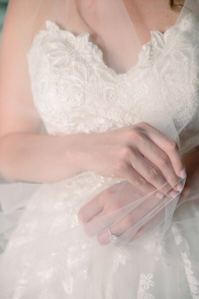 Film Wedding Photographer - Caitlin Wilcox Photography | closeup picture of a bride delicately holding her veil around her - links to feature gallery page for a destination wedding on the coast of Spain