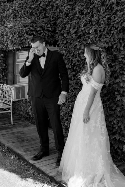 Groom wipes away tears during emotional first look with bride in lace gown at The Cottage on Lake Fairview in Orlando, Florida.