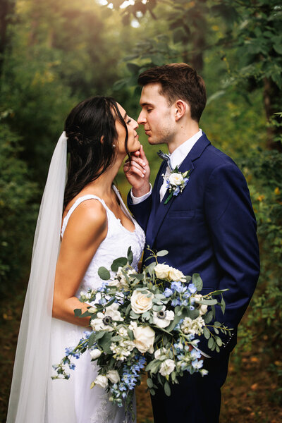 Groom gently holds brides chin, his love and admiration evident  in his touch