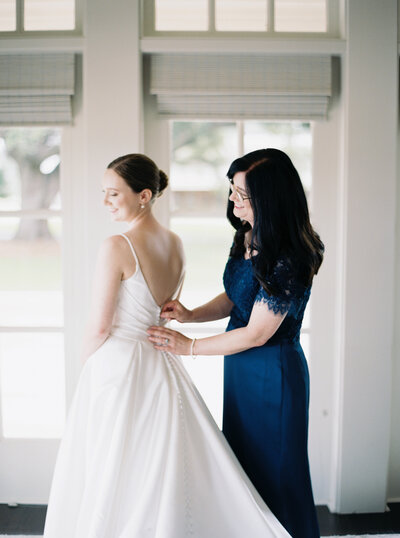 Bride’s mother helping button her wedding dress in a touching moment at Oak Crossing Wedding in Lake Charles, captured by Morgan Alysse, Lafayette wedding photographer.