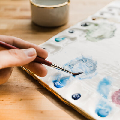 close up photo of PNW artist Amy Duffy using a paintbrush on a palette created by Pottery by Eleni