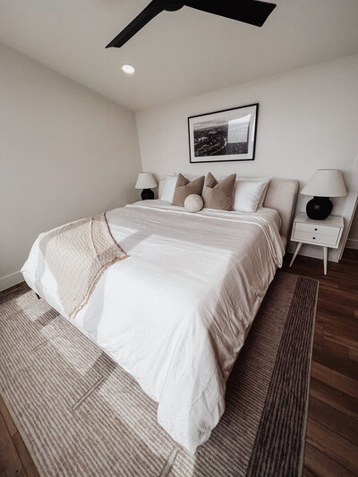 Bedroom with bed with white covers and tan pillows