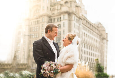photo of a bride and groom outside the royal liver building in liverpool in the snow