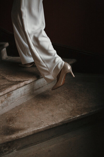 Bride in suit walks up the stairs to ceremony - artistic shot
