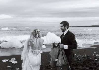 groom puts a jacket on his bride during their iceland adventure elopement
