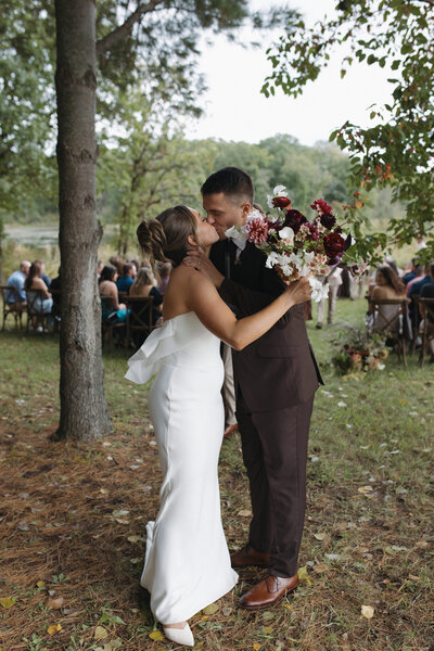 Couple kissing at the end of the aisle after their intimate wedding ceremony in northern Minnesota. Captured by Minnesota Wedding and Elopement Photographer specializing in couples looking for an intimate, documentary style wedding day coverage. 
