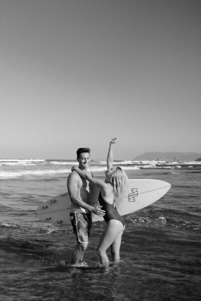 man and women on the beach in mexico with surfboard
