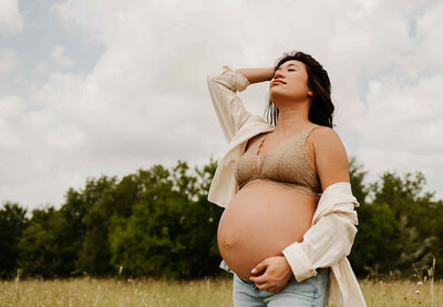 maternity mom posting in paula goforth studio located in azle with a lifestyle background mom is dressed in jeans and open white shirt