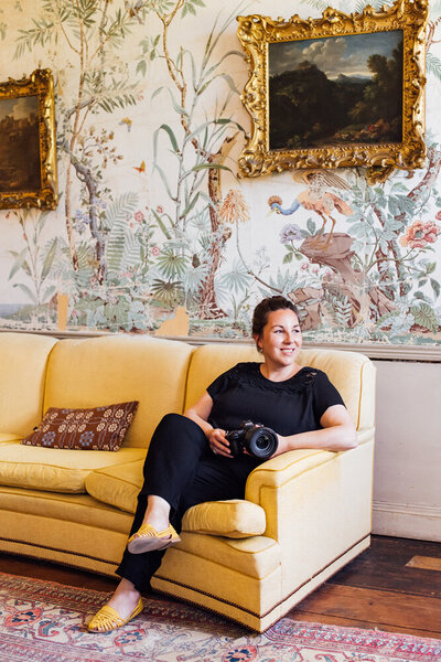 Wedding photographer Sarah Vivienne stting on a yellow sofa in a country house