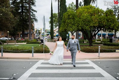 Bride and Groom hold hands as they cross the street through the circle in Old Towne Orange
