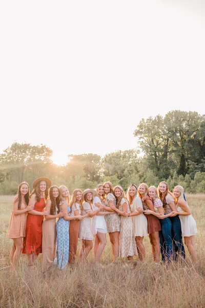 Rachel B Photography's Senior Rep Team of 14 seniors stand together in a line to hug each other and smile at the camera.
