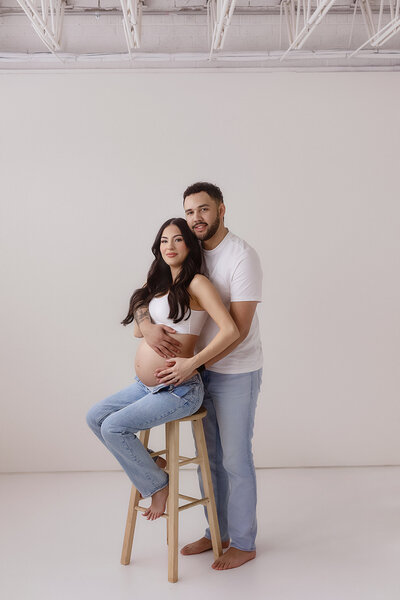 expecting couple posing in denver maternity studio for photographer