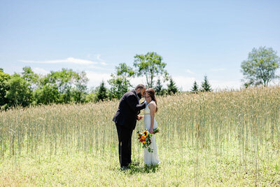 Bride and groom posing in a field of tall grass