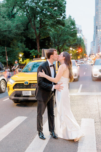 Bride and groom kissing in a crosswalk on a city street