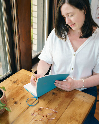 Copywriter Kat Jackson planning client work in a blue notebook.