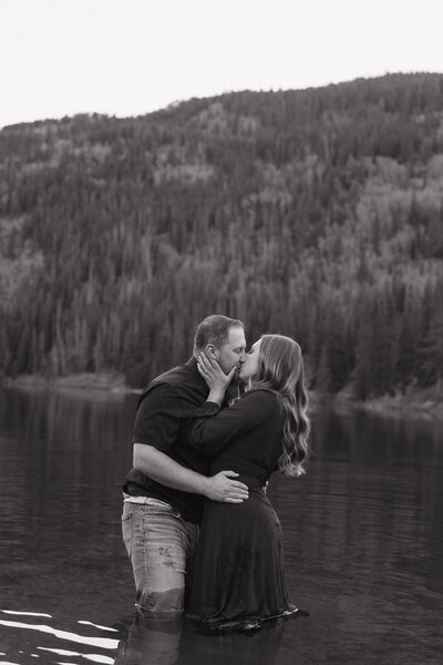a couple standing in the water while kissing