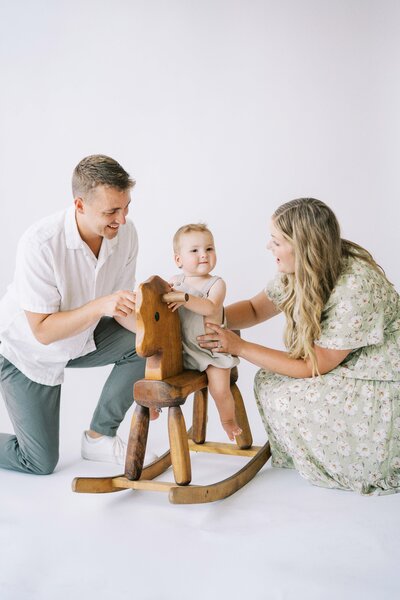 parents watching their baby play on a rocking chair