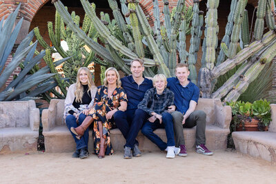 A family of five sitting on a bench at the Mission San Juan Capistrano